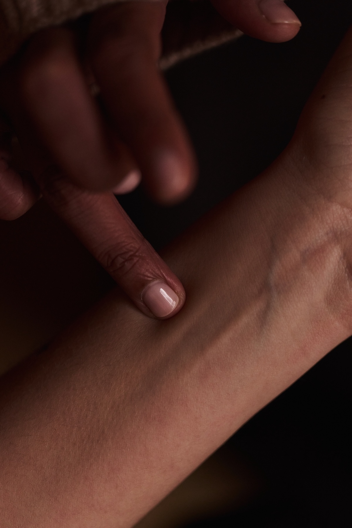 Close-up of a hand feeling a pulse of another person.
